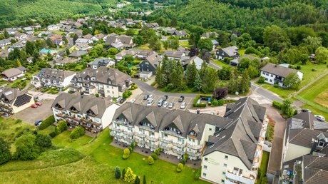 Ferien in der Eifel: ein erster Einblick Luftaufnahme von Ferienpark-Siedlung mit bewaldeten Hügeln im Hintergrund