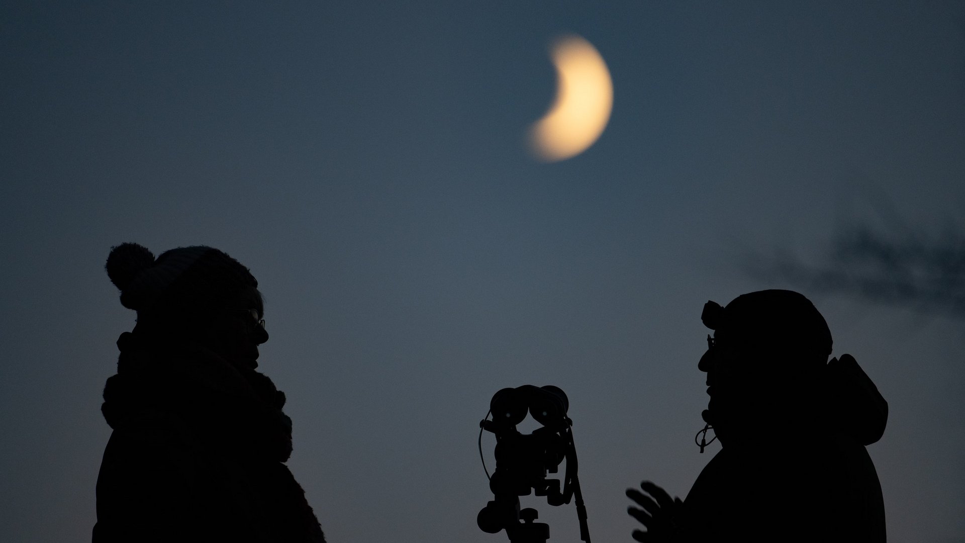 Sternenpark Eifel erleben – Urlaub unter dem Sternenhimmel Silhouetten von Personen beobachten partielle Sonnenfinsternis mit Teleskop bei Abenddämmerung