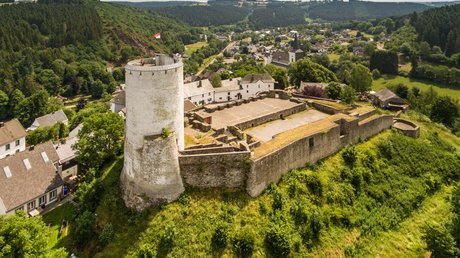 Ferien in der Eifel: ein erster Einblick Luftaufnahme einer alten Burganlage mit runden Turm in grüner Hügellandschaft