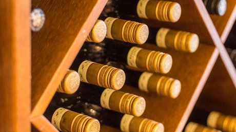 Ferien in der Eifel: ein erster Einblick Weinflaschen liegen in einem Holzweinregal mit diagonalen Fächern
