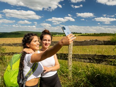 Wohnung mieten in Gemünd? Da haben wir was für Sie! Zwei Frauen machen Selfie vor einem Holzzaun auf dem Land bei sonnigem Wetter