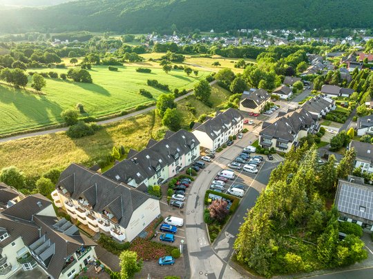 Wohnung mieten in Gemünd? Da haben wir was für Sie! Luftaufnahme eines Wohngebiets an einer grünen Waldlichtung im Sommer