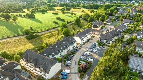 Ferien in der Eifel: ein erster Einblick Luftaufnahme eines Wohngebiets an einer grünen Waldlichtung im Sommer