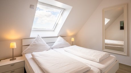 Ferien in der Eifel: ein erster Einblick Helles Schlafzimmer mit Dachfenster, Doppelbett und Nachttischen mit Lampen