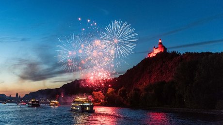 Ferien in der Eifel: ein erster Einblick Feuerwerk über dem Fluss mit beleuchtetem Schloss bei Abenddämmerung und Booten auf dem Wasser