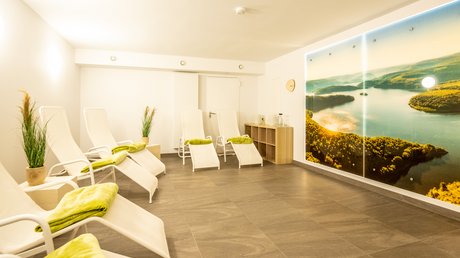Ferien in der Eifel: ein erster Einblick Heller Spa-Raum mit weißen Liegen und Wandbild eines Flusses