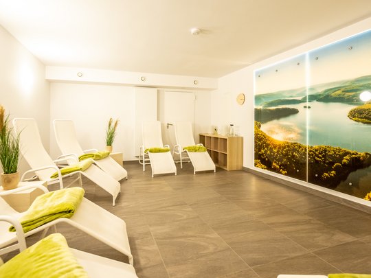Alle aktuellen Angebote, Specials und Raten im Gemünder Ferienpark Salzberg – perfekt für euren Urlaub im Nationalpark Eifel. Heller Spa-Raum mit weißen Liegen und Wandbild eines Flusses