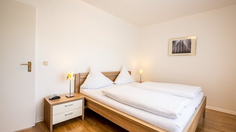 Ferien in der Eifel: ein erster Einblick Helles Schlafzimmer mit Doppelbett, Nachttisch und Lampen