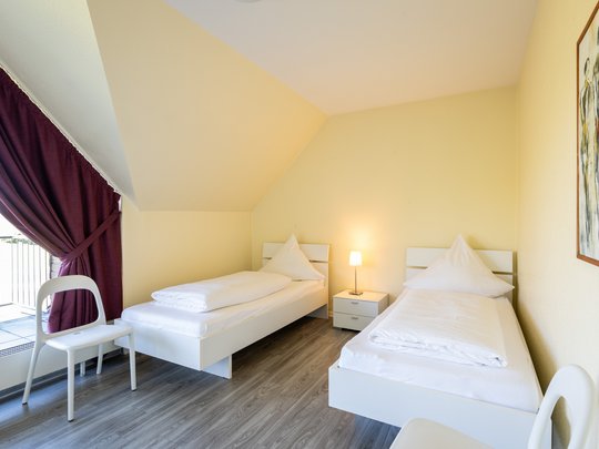 Wohnung mieten in Gemünd? Da haben wir was für Sie! Hell eingerichtetes Schlafzimmer mit zwei Einzelbetten und Nachttischlampe