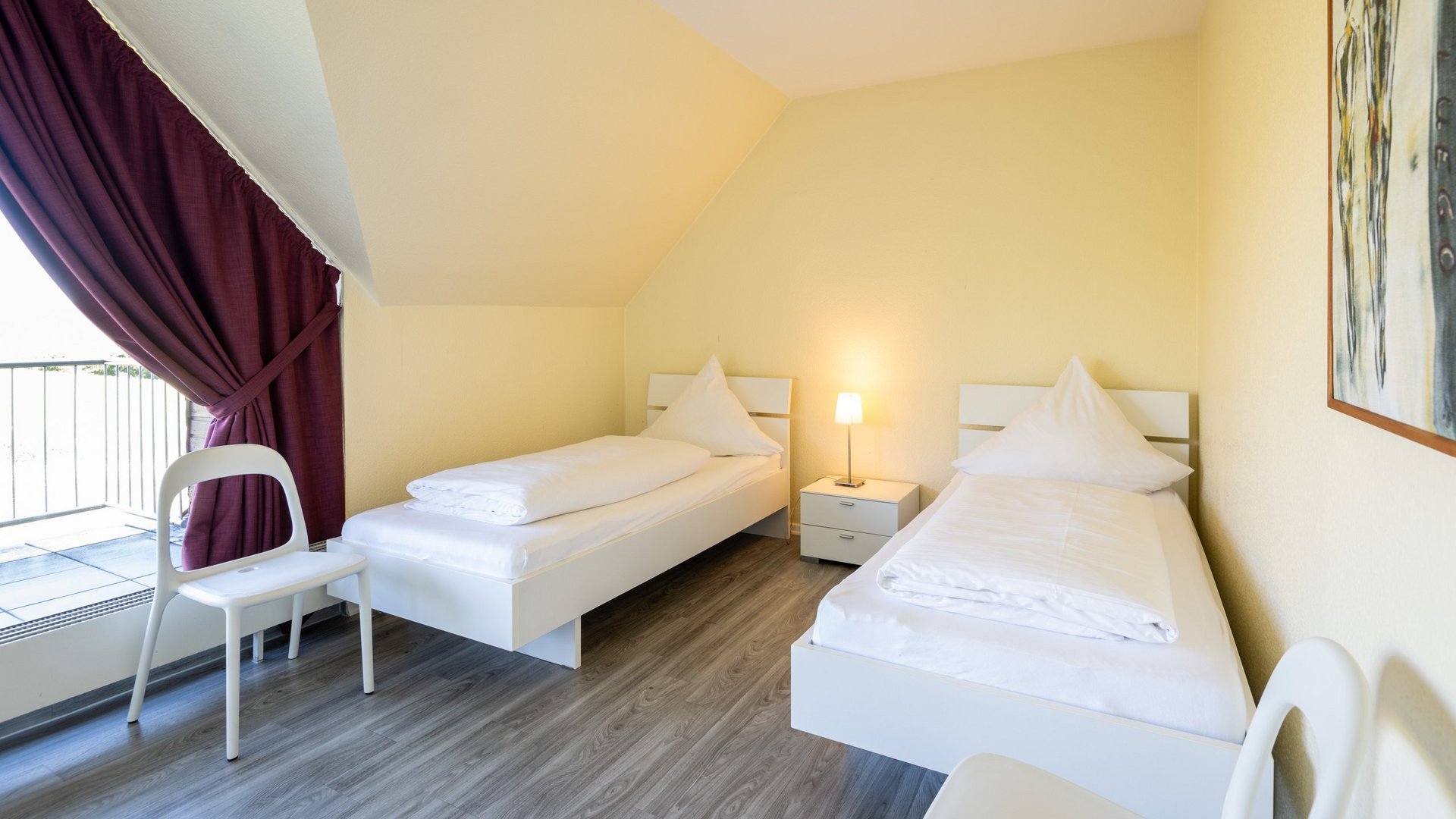 Ihre Unterkunft in Gemünd – Langzeitaufenthalt mit extra Service Hell eingerichtetes Schlafzimmer mit zwei Einzelbetten und Nachttischlampe