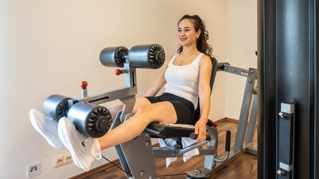 Ferien in der Eifel: ein erster Einblick Frau trainiert Beine an Beinstreckmaschine im Fitnessstudio