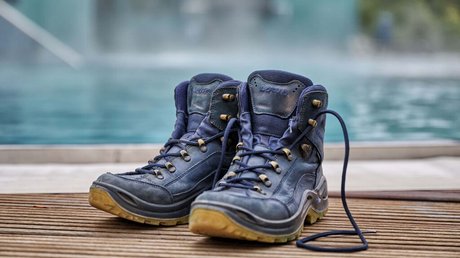 Ferien in der Eifel: ein erster Einblick Paar blaue Wanderschuhe auf Holzterrasse neben Wasser