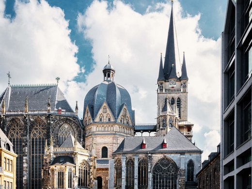 Urlaub in Deutschland: Von der Eifel aus Städte erkunden Historische Kirche mit kleinem Platz und Kopfsteinpflaster bei sonnigem Wetter