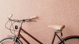 Eifel-Urlaub: Insidertipps aus Gemünd Rotes Vintage-Fahrrad vor texturierter rosa Wand