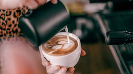 Eifel-Urlaub: Insidertipps aus Gemünd Barista gießt Milch in Cappuccino für Latte Art in weißer Tasse