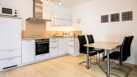 Ferien in der Eifel: ein erster Einblick Moderner Küchenbereich mit Esstisch und schwarzen Stühlen