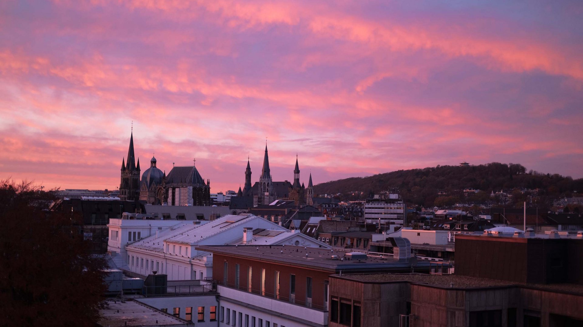 Urlaub in Deutschland: Von der Eifel aus Städte erkunden Stadtansicht bei Sonnenuntergang mit rosa Himmel und Kirchtürmen