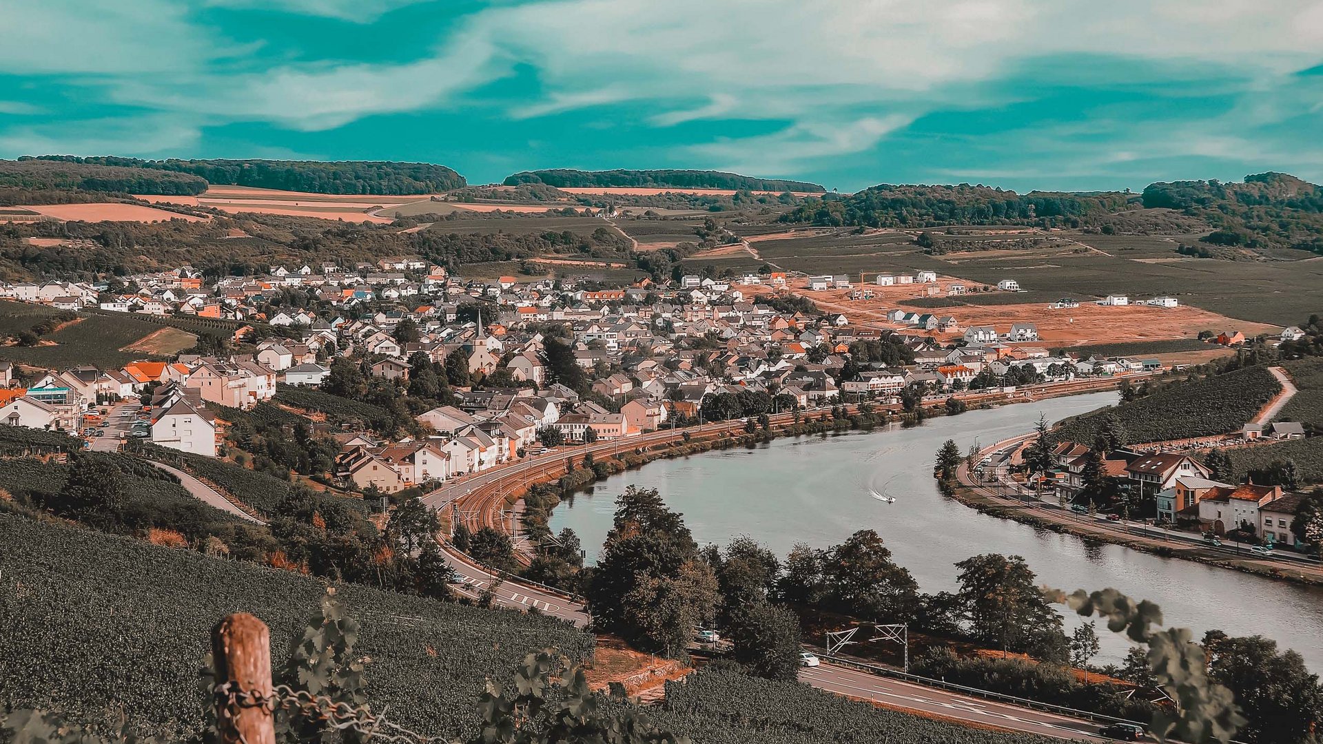 Urlaub in Deutschland: Von der Eifel aus Städte erkunden Blick auf eine Stadt an einem Fluss mit Weinbergen und Hügeln im Hintergrund