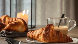 Eifel-Urlaub: Insidertipps aus Gemünd Croissant auf Teller mit Kaffee und Kerze im Hintergrund