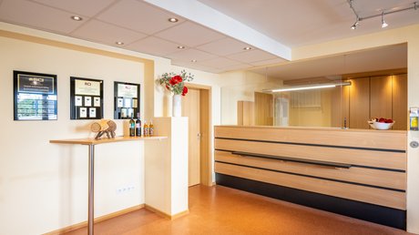 Ferien in der Eifel: ein erster Einblick Heller Empfangsbereich mit Holztresen und dekoriertem Stehtisch