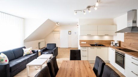 Ferien in der Eifel: ein erster Einblick Helle moderne Wohnküche mit Esstisch, Küche und Sitzecke unter Dachschräge