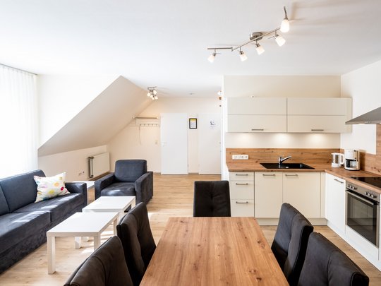 Ihre Unterkunft in Gemünd – Langzeitaufenthalt mit extra Service Helle moderne Wohnküche mit Esstisch, Küche und Sitzecke unter Dachschräge