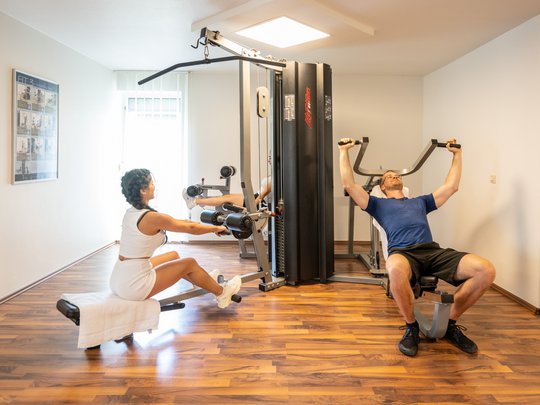 Ferienwohnungen in Gemünd mit dem gewissen Extra Zwei Personen trainieren an Fitnessgeräten in einem hellen Raum mit Holzboden
