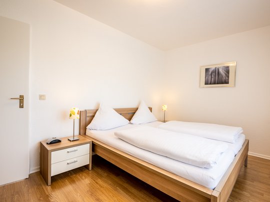 Ferienwohnungen in Gemünd mit dem gewissen Extra Helles Schlafzimmer mit Doppelbett, Nachttisch und Lampen