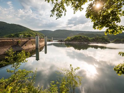 Holidays in the Eifel region: Want a change of pace? Reservoir with dam and green hills on a sunny day