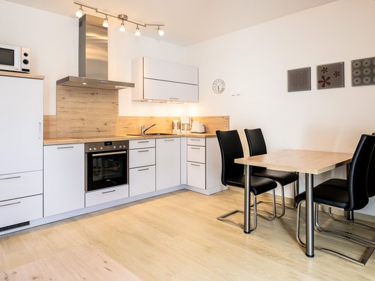 Ferienwohnungen in Gemünd mit dem gewissen Extra Moderner Küchenbereich mit Esstisch und schwarzen Stühlen