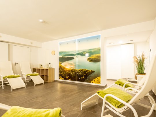 Ferienwohnungen in Gemünd mit dem gewissen Extra Ruheraum mit Liegestühlen und Landschaftsfoto an der Wand