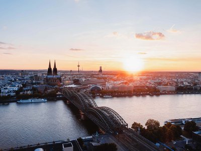 Holidays in the Eifel region: Want a change of pace? Sunset over Cologne with Rhine river, Hohenzollern Bridge, and Cologne Cathedral